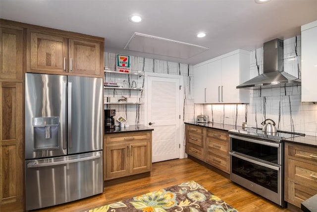 1875 Ski Time Square Dr Unit 711, Steamboat Springs, CO 80487 - kitchen with stainless steel appliances, backsplash, dark countertops, and wall chimney range hood