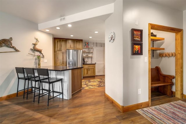 1875 Ski Time Square Dr Unit 711, Steamboat Springs, CO 80487 - kitchen featuring a kitchen breakfast bar, stainless steel fridge, baseboards, a peninsula, and dark wood-type flooring