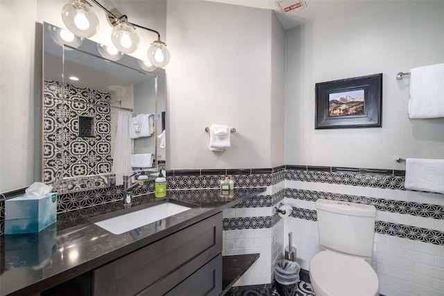 1875 Ski Time Square Dr Unit 711, Steamboat Springs, CO 80487 - full bathroom with tile walls, toilet, vanity, and wainscoting