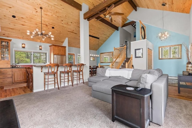 1750 Fish Creek Falls Rd, Steamboat Springs, CO 80487 - living room featuring a chandelier, wood ceiling with exposed beams, high vaulted ceiling, stairs, and light colored carpet