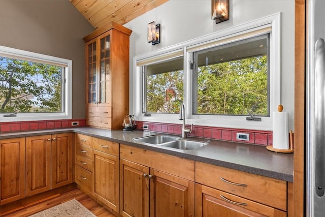 1750 Fish Creek Falls Rd, Steamboat Springs, CO 80487 - kitchen featuring a sink, dark countertops, brown cabinetry, glass insert cabinets, and light wood finished floors