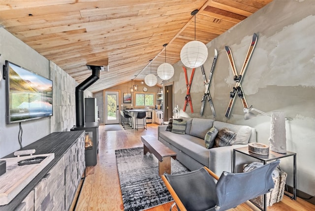 living area featuring vaulted ceiling, wooden ceiling, a wood stove, and light wood-type flooring