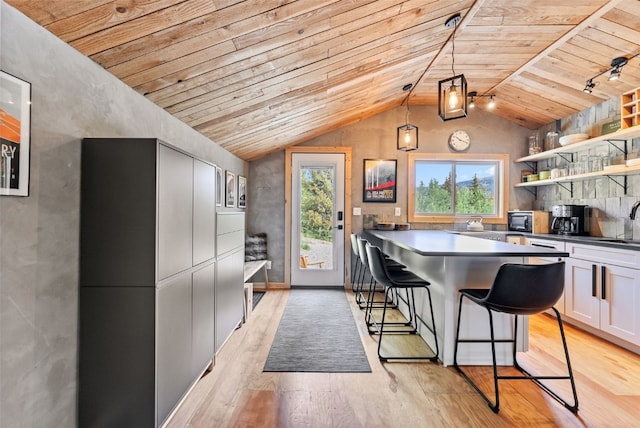 kitchen with open shelves, light wood-type flooring, wooden ceiling, lofted ceiling, and a breakfast bar
