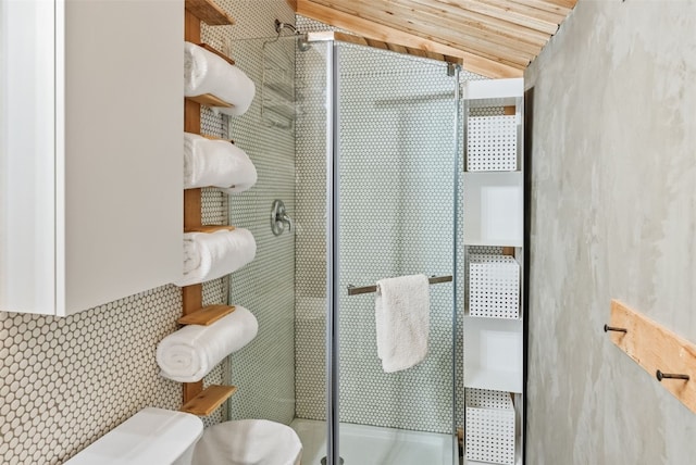 full bath featuring decorative backsplash, toilet, vaulted ceiling, and a shower stall