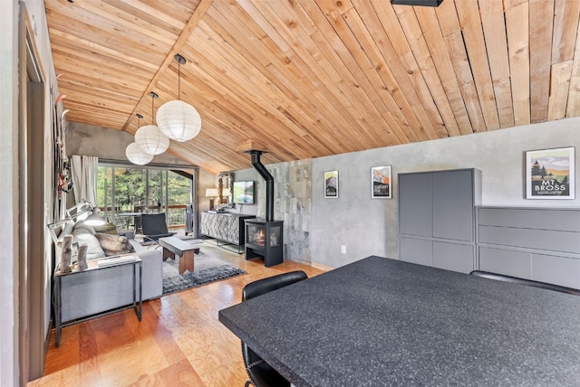 dining space with a wood stove, wood finished floors, vaulted ceiling, and wooden ceiling