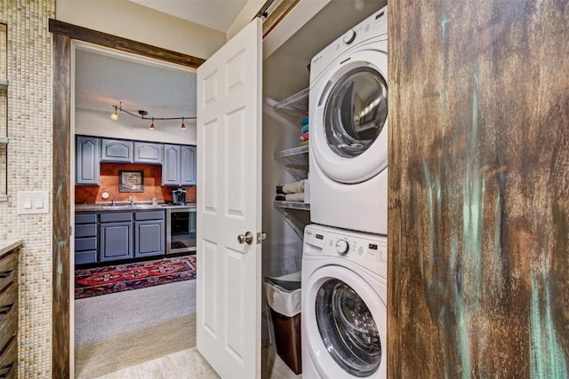 washroom with track lighting, laundry area, stacked washer / drying machine, carpet flooring, and wine cooler