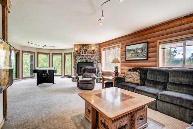 living area with a fireplace, track lighting, log walls, and light colored carpet