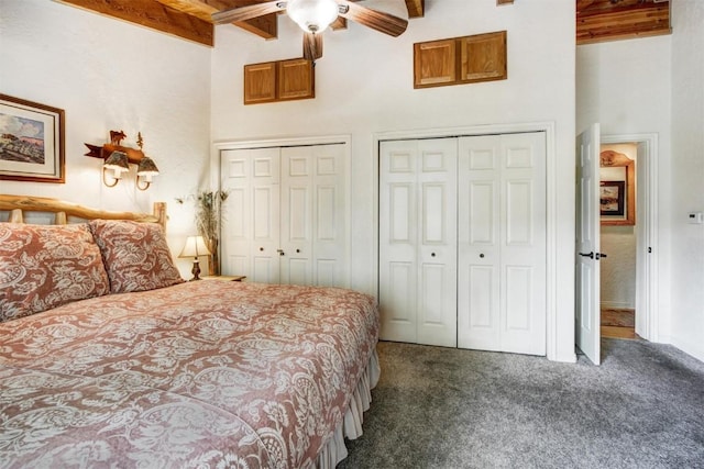 bedroom with carpet floors, a towering ceiling, multiple closets, and beamed ceiling
