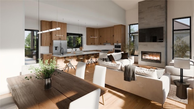 dining room featuring a high ceiling, plenty of natural light, a fireplace, and light wood-type flooring