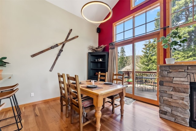 960 Whispering Pines Ln, Breckenridge, CO 80424 - dining space with hardwood / wood-style floors, healthy amount of natural light, a stone fireplace, and a towering ceiling
