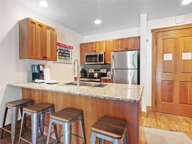 20 Hunki Dori Ct Unit 2212, Keystone, CO 80435 - kitchen with stainless steel appliances, a peninsula, light wood-style flooring, a sink, and a kitchen breakfast bar