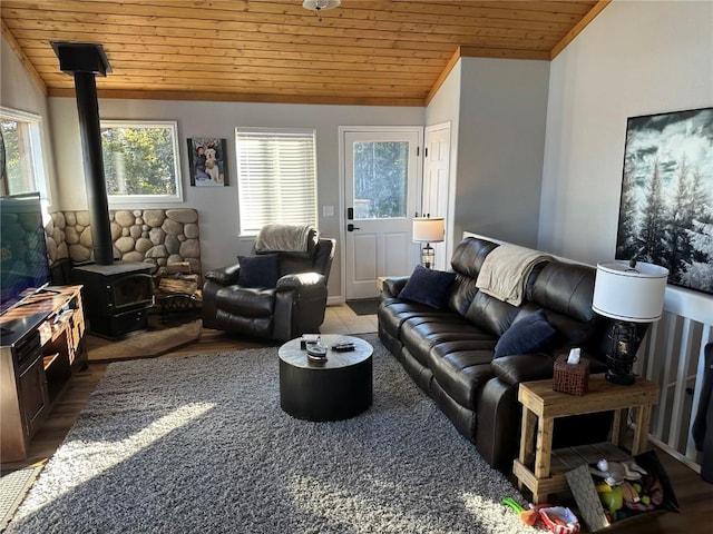 living area featuring vaulted ceiling, a wood stove, and wood ceiling