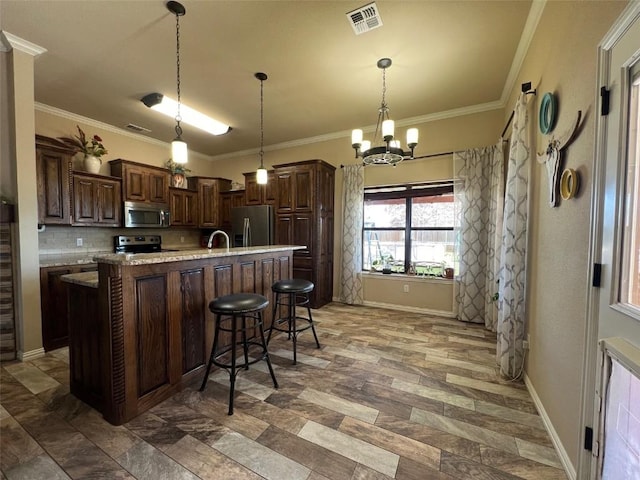 kitchen featuring an island with sink, stainless steel appliances, backsplash, visible vents, and a chandelier
