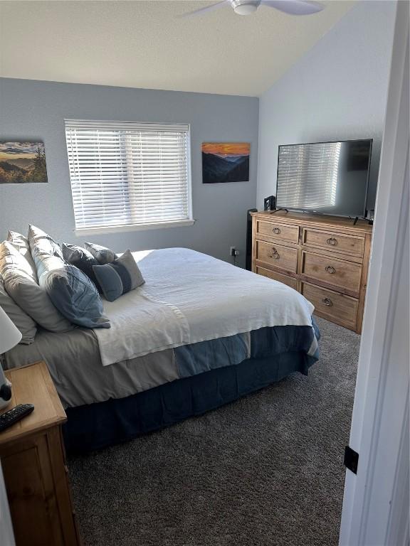 bedroom with vaulted ceiling, carpet, and a ceiling fan