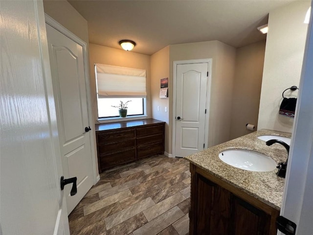 bathroom with stone finish floor, vanity, and baseboards