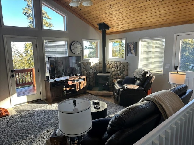 living area with lofted ceiling, a wood stove, and wood ceiling