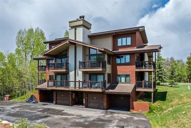 1655 Ranch Rd Unit 403, Steamboat Springs, CO 80487 - rear view of house featuring a chimney, a balcony, a lawn, and driveway