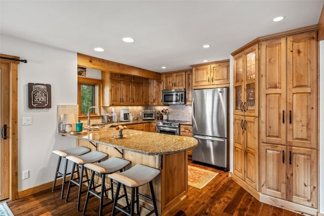 1655 Ranch Rd Unit 403, Steamboat Springs, CO 80487 - kitchen with appliances with stainless steel finishes, a peninsula, recessed lighting, backsplash, and light stone counters