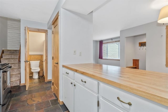 6 Sequoia Ct Unit 6, Steamboat Springs, CO 80487 - kitchen with stainless steel electric range, stone tile floors, white cabinetry, wooden counters, and baseboards