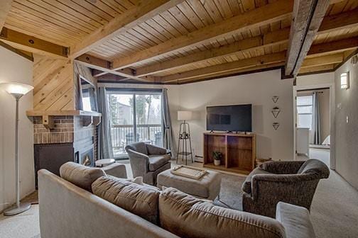 8500 Ryan Gulch Rd Unit 101, Silverthorne, CO 80498 - carpeted living room featuring a fireplace, healthy amount of natural light, wooden ceiling, and beamed ceiling