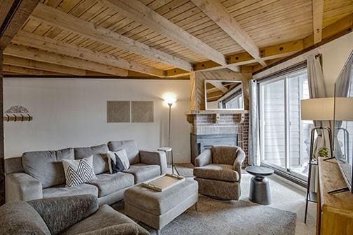 8500 Ryan Gulch Rd Unit 101, Silverthorne, CO 80498 - carpeted living room with beamed ceiling, wooden ceiling, and a fireplace