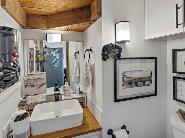 bathroom featuring wood ceiling, a sink, and toilet