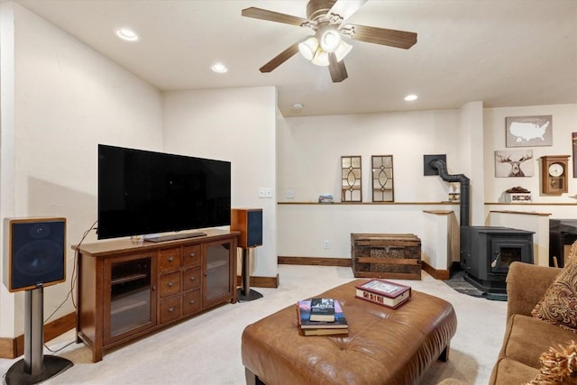 living area featuring a ceiling fan, a wood stove, baseboards, light carpet, and recessed lighting