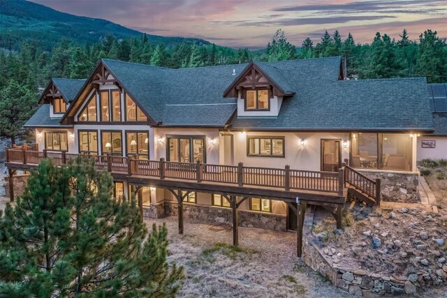 70 County Road 26, Twin Lakes, CO 81251 - back of property at dusk with stone siding, roof with shingles, a deck with mountain view, and stucco siding
