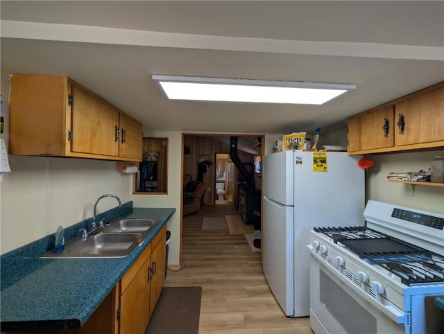 kitchen featuring brown cabinetry, white range with gas cooktop, a sink, and light wood-style flooring