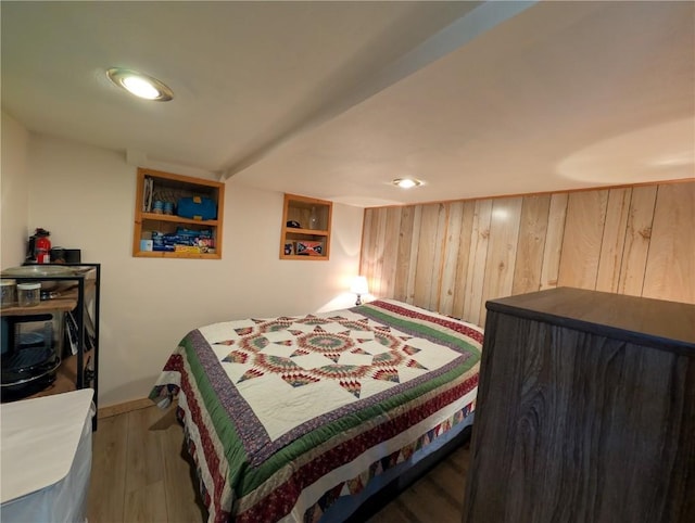 bedroom with baseboards, wood walls, and wood finished floors