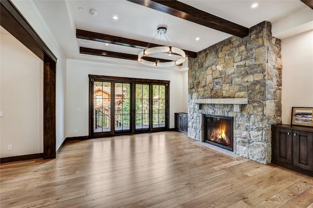 77 E Trade Ct, Keystone, CO 80435 - unfurnished living room with beam ceiling, light wood-type flooring, a stone fireplace, and baseboards