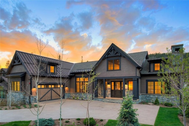 77 E Trade Ct, Keystone, CO 80435 - back of property at dusk with stone siding, a standing seam roof, and driveway