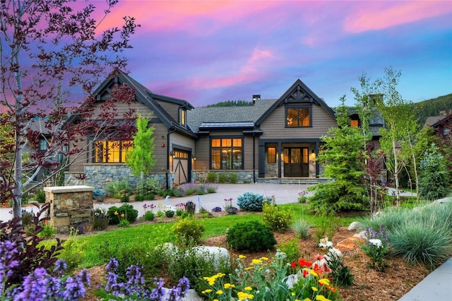 77 E Trade Ct, Keystone, CO 80435 - back of property at dusk with an attached garage, driveway, and stone siding