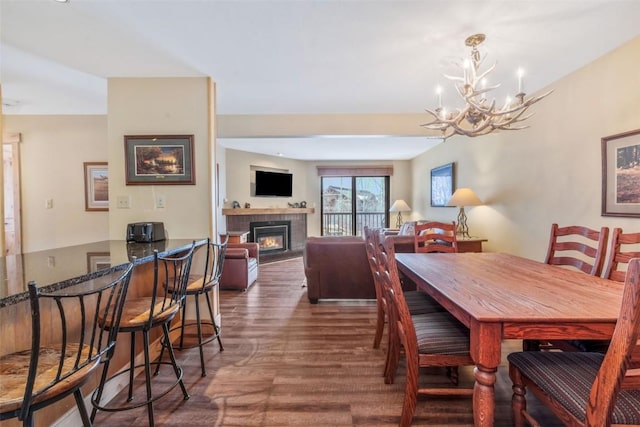 dining area with a chandelier, wood finished floors, and a tiled fireplace