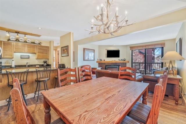dining room featuring recessed lighting, a chandelier, light wood-style floors, and a tiled fireplace