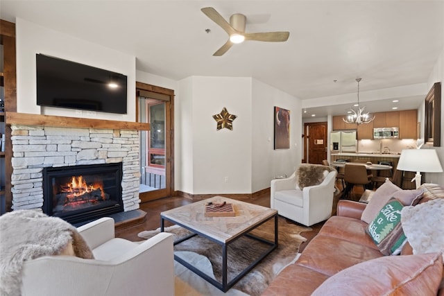 living room featuring a fireplace, dark hardwood / wood-style floors, ceiling fan with notable chandelier, and sink