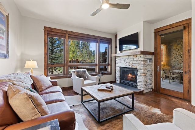 living room featuring a fireplace, ceiling fan, and dark wood-type flooring