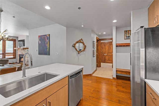 kitchen featuring a stone fireplace, sink, light wood-type flooring, and stainless steel appliances