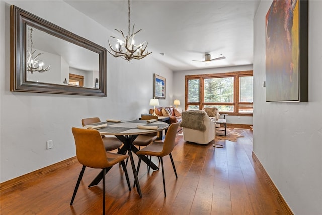 dining space with wood-type flooring and ceiling fan with notable chandelier