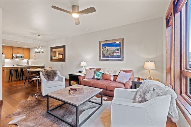 living room featuring ceiling fan with notable chandelier and light hardwood / wood-style flooring