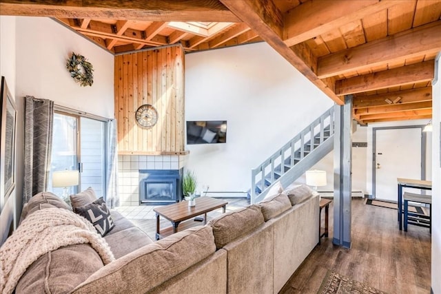 8300 Ryan Gulch Rd Unit F306, Silverthorne, CO 80498 - living room featuring stairway, dark wood-type flooring, a tiled fireplace, a baseboard heating unit, and beam ceiling