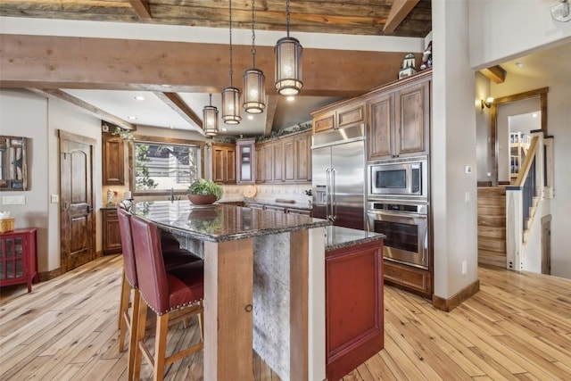 28 Tieze Ln, Keystone, CO 80435 - kitchen with built in appliances, beam ceiling, light wood-style flooring, a kitchen island, and dark stone counters