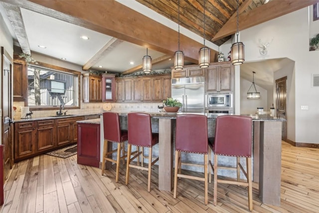 28 Tieze Ln, Keystone, CO 80435 - kitchen featuring built in appliances, a kitchen island, light wood finished floors, backsplash, and a kitchen breakfast bar