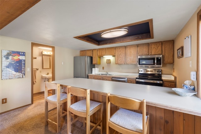 160 Creekside Dr Unit 3, Frisco, CO 80443 - kitchen with stainless steel appliances, a sink, brown cabinetry, light countertops, and a kitchen bar