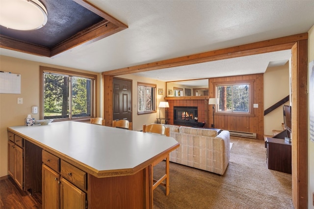 160 Creekside Dr Unit 3, Frisco, CO 80443 - kitchen featuring a tile fireplace, plenty of natural light, a peninsula, light countertops, and beamed ceiling