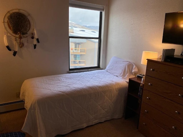 carpeted bedroom featuring a baseboard heating unit