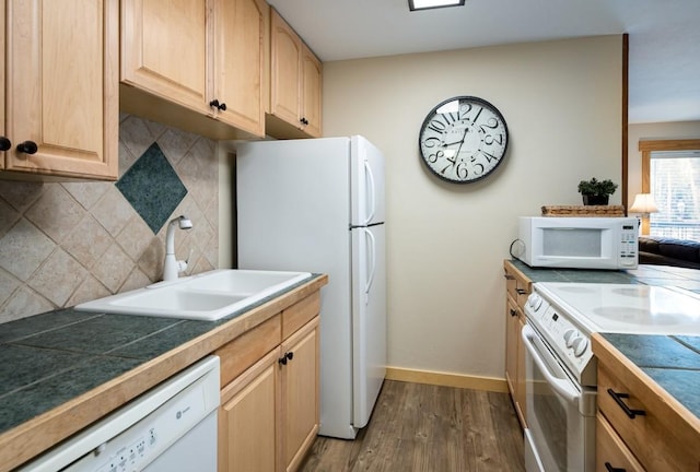 kitchen featuring dark wood finished floors, light brown cabinetry, a sink, white appliances, and decorative backsplash