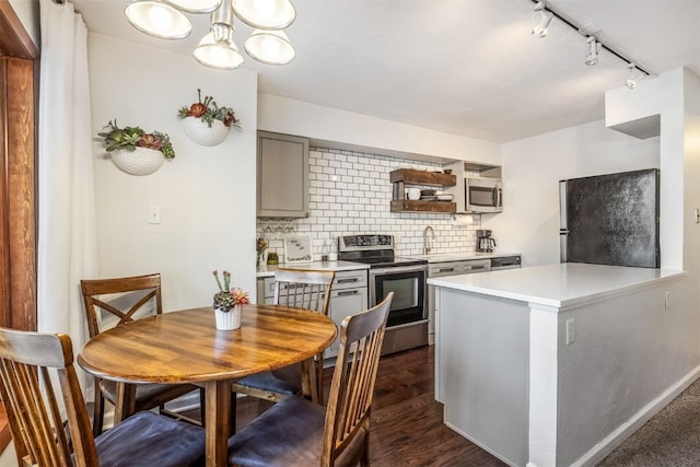 kitchen featuring gray cabinets, stainless steel appliances, light countertops, rail lighting, and backsplash