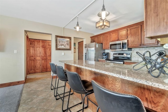 1995 Storm Meadows Dr Unit 307, Steamboat Springs, CO 80487 - kitchen featuring stainless steel appliances, a peninsula, brown cabinetry, backsplash, and light stone counters