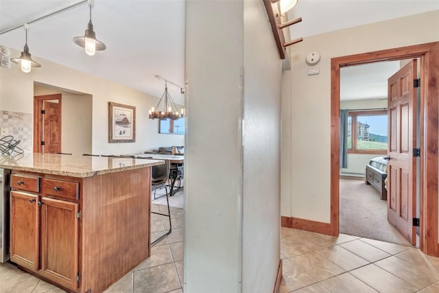 1995 Storm Meadows Dr Unit 307, Steamboat Springs, CO 80487 - kitchen with a chandelier, light stone countertops, pendant lighting, brown cabinetry, and a breakfast bar